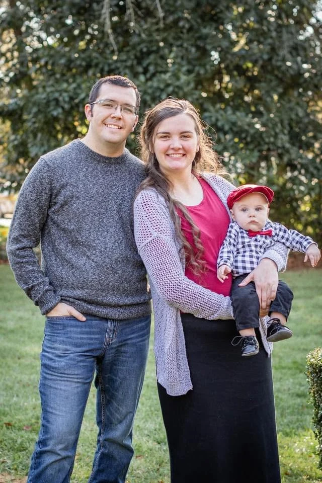 Joseph Stephens outdoors with his wife and young daughter
